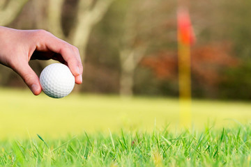 golf ball in  course with red  flag unfocused