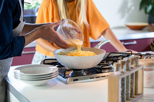 Midsection of man pouring batter into saucepan at home