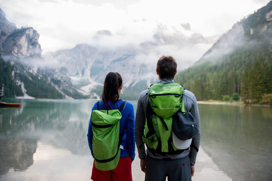 Rear view of couple standing near lake against mountain