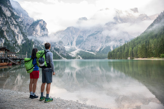 Rear view of couple standing near lake against mountain