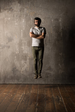Portrait of man jumping against concrete wall