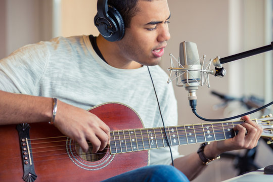 Man singing with guitar while sitting in studio