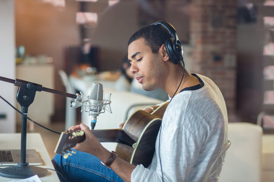 Man singing with guitar while sitting in studio