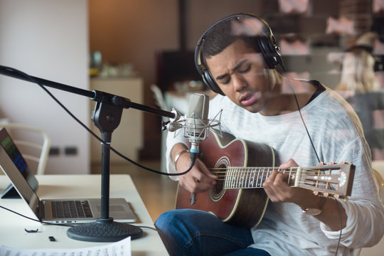 Man singing with guitar while sitting in studio
