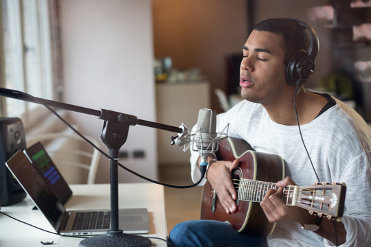 Man singing with guitar while sitting in studio