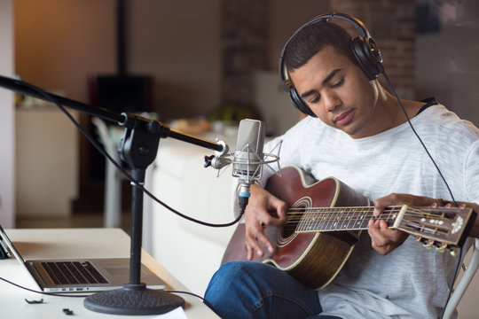 Man singing with guitar while sitting in studio