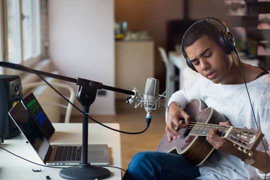 Man singing with guitar while sitting in studio