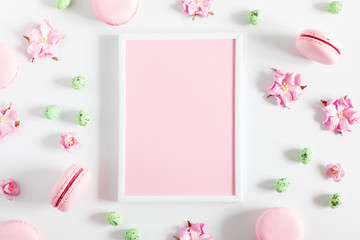 Easter decor, composition. Blank frame for text, flowers, macaroon, easter eggs on white background. Flat lay, top view, copy space 