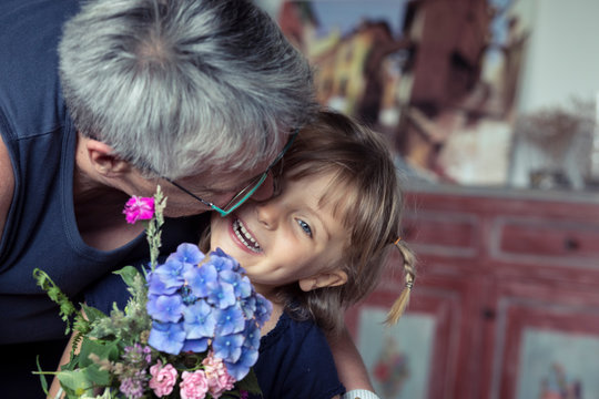 Grandmother kissing her granddaughter at home