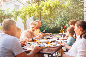 Big multigeneration family have dinner on open garden terrace