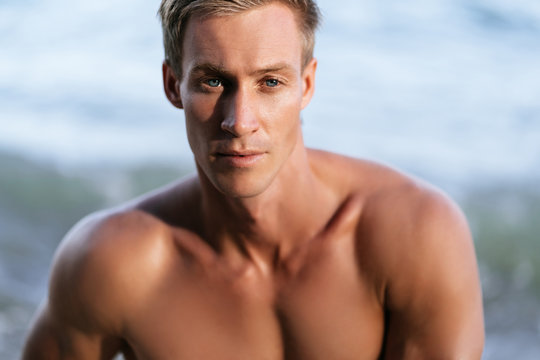 Portrait of sexy muscular man with bare-chested posing on camera at beach