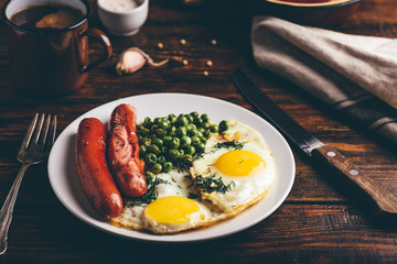 Breakfast with fried eggs, sausages and green peas