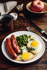 Breakfast with fried eggs, sausages and green peas