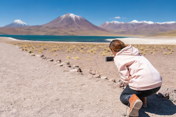 Women hiker looking at views in an amazing wilderness environment at Atacama Desert Andes mountains lagoons at Lagunas Altiplanicas. A woman cut out silhouette over the awe Andean Altiplano scenery
