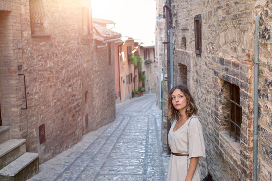 Young woman standing against wall in alley