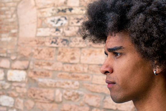 Close up of afro young man against brick wall