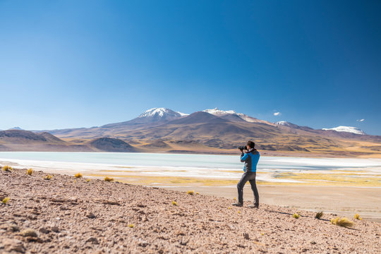 Landscape man photographer taking photos in an amazing wilderness environment at Atacama Desert Andes mountains lagoons. A man cut out silhouette over the awe Tuyajto Lagoon scenery at Altiplano
