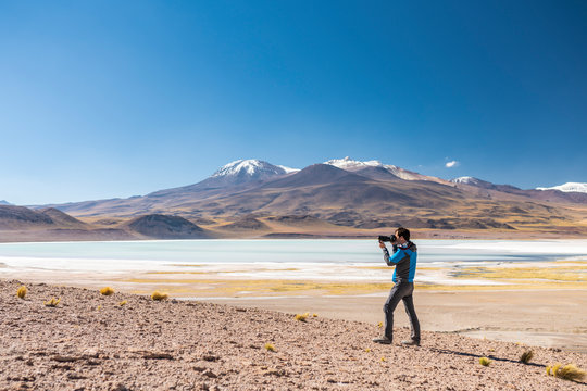 Landscape man photographer taking photos in an amazing wilderness environment at Atacama Desert Andes mountains lagoons. A man cut out silhouette over the awe Tuyajto Lagoon scenery at Altiplano
