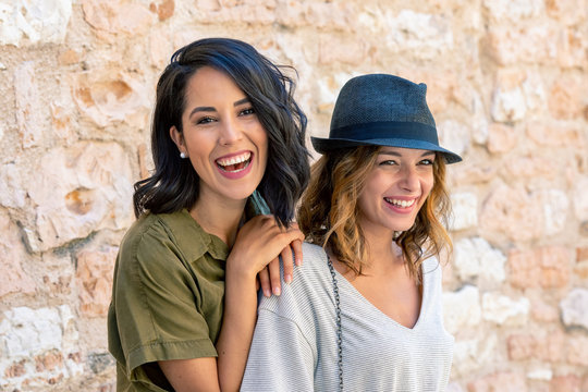 Portrait of smiling friends standing against brick wall