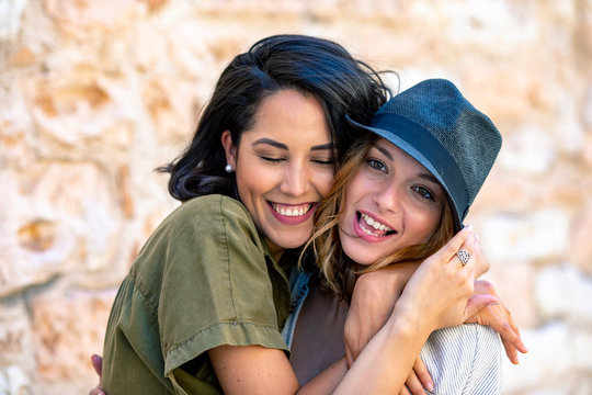 Smiling friends embracing against brick wall