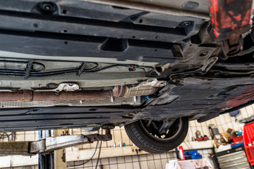 The exhaust system in the car seen from below, the car is on the lift in the car workshop.