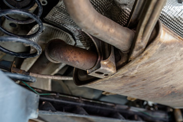 The exhaust system in the car seen from below, the car is on the lift in the car workshop.
