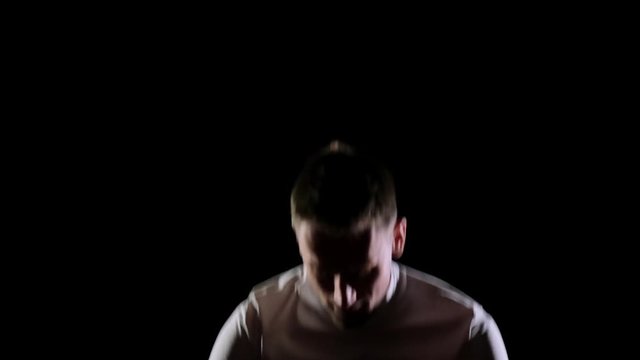 Athletic man in white clothes performs tricks jumping on a trampoline on a black monophonic background