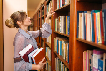 Woman takes book from shelf in university library