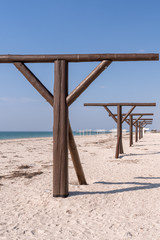 Vertical. Wooden brown umbrella supports stand in a row in the resort town by the sea in the spring in the off-season. 