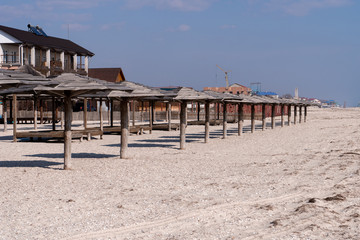 The resort town with wooden umbrellas on the sandy-beach seashore. 