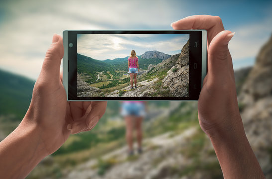 Girl in a mountain valley on smartphone screen