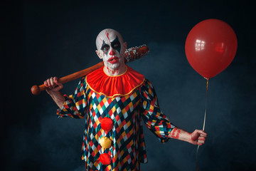 Ugly bloody clown with baseball bat and balloon