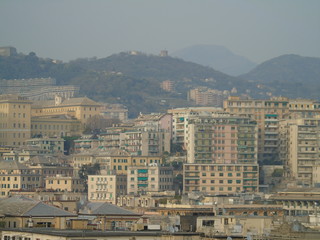 Genova, Italy - 04/02/2019: An amazing caption of the city of Genova from the hills in winter days, with a great grey sky, some tall skyscrapers and beautiful old buildings