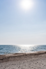 Fototapeta premium Vertical. Sand-shell seashore in the afternoon during sunny weather in summer