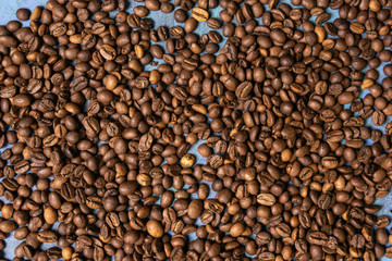 Roasted coffee beans in bulk on a blue background