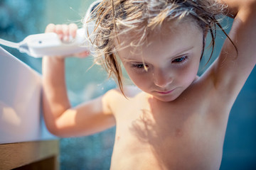 Blond girl drying her hair with hair dryer in bathroom