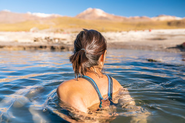 Woman taking a bath at El Tatio Geysers hot springs at Atacama desert, amazing thermal spring...