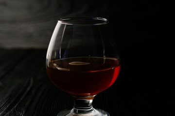 Cognac in a glass on a wooden background with ice