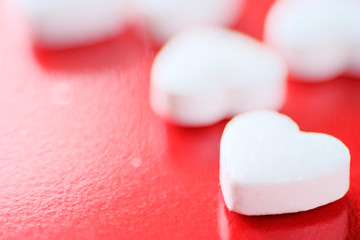 The heart is white on a red background. A white heart-shaped pill. Red background. The drug for the treatment of heart disease.