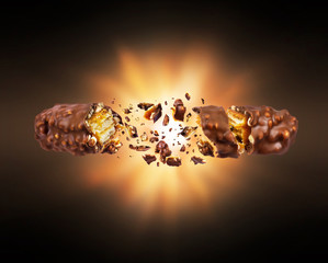Waffle chocolate bar with nuts crushed in the air in the dark