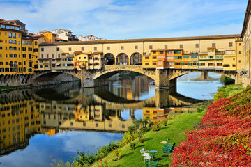 Uitzicht op de historische Ponte Vecchio met reflecties in de rivier de Arno in de herfst, Florence, Toscane, Italië