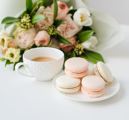 Obraz na płótnie Canvas Elegant sweet dessert macarons, cup of coffee and pastel colored beige flowers bouquet