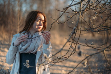 Portrait of a girl with willow branches in early spring at sunset.