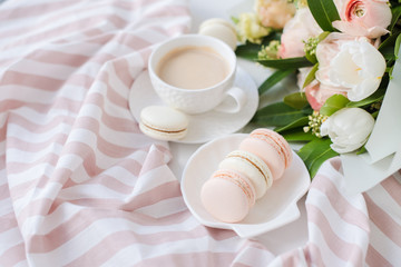Elegant sweet dessert macarons, cup of coffee and pastel colored beige flowers bouquet
