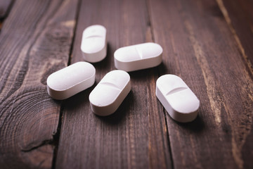 Fototapeta na wymiar Large white pills, antidepressants on a wooden background, close-up