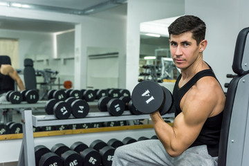 Man in gym holding dumbbell close up