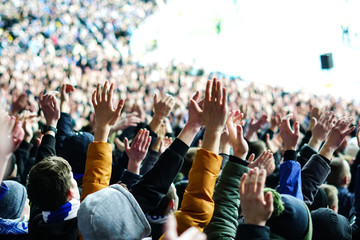Vintage style photo of a crowd, happy people enjoying rock concert, raised up hands and clapping of pleasure, active night life concept
