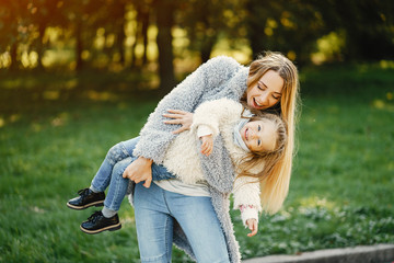 young blonde mother spinning around her toddler daughter in the park on a sunny day