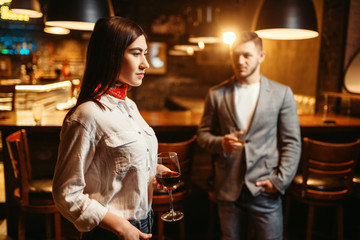 Woman flirting against man, couple in bar