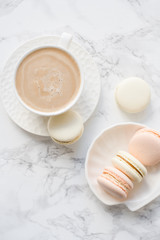 Elegant sweet dessert macarons and cup of coffee on white marble table